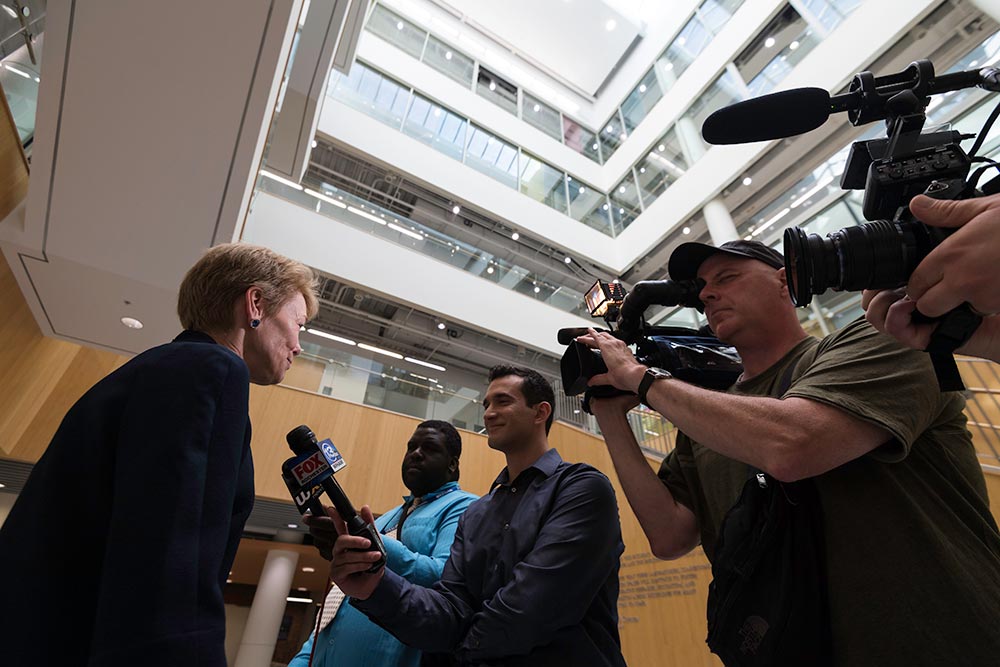 Sarah Mantgesdorf surrounded by reporters with microphones and cameras.
