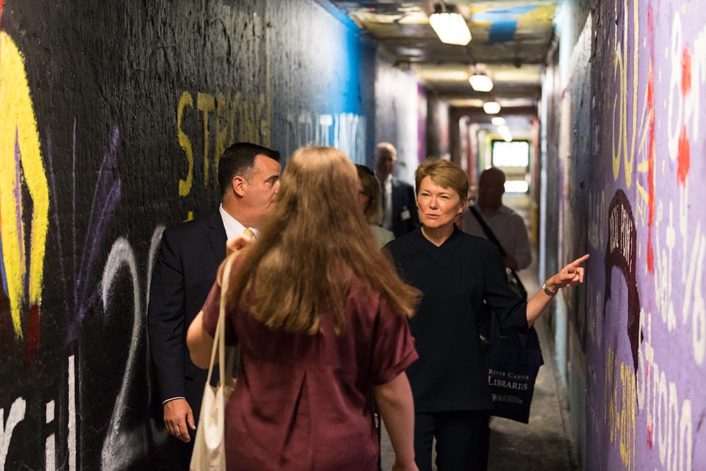 large group of people walking through tunnels colorfully painted.