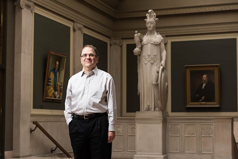Narayana Kocherlakota standing next to a statue in the library.