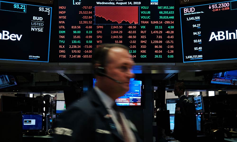 Feature image scene from New York Stock Exchange, with bar chart pointing downward as a stock broker walks past it.