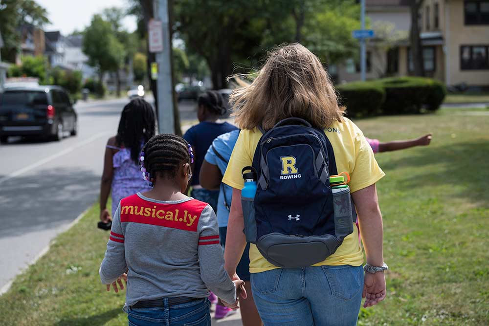 one student walking, while holding a child's hand.