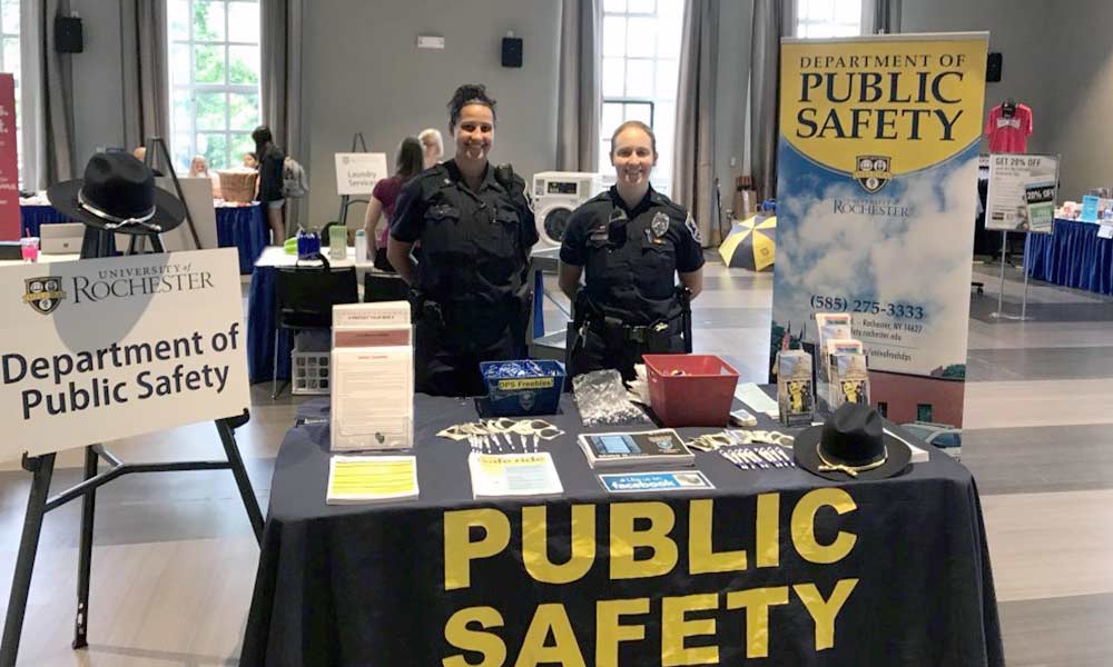 two police officers standing behind a table a the orientation fair, the table has a sign that reads PUBLIC SAFETY