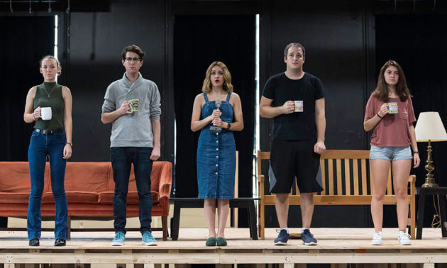 five actors stand on a stage