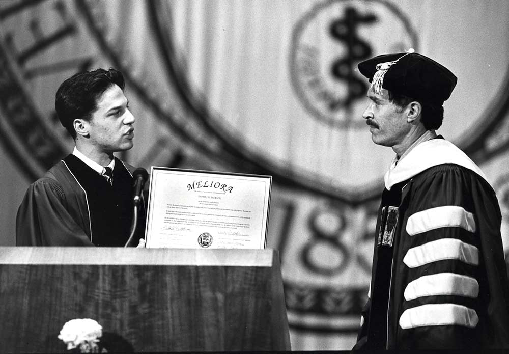 student and president on University stage in academic robes
