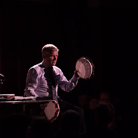 percussionist on stage with two tambourines.