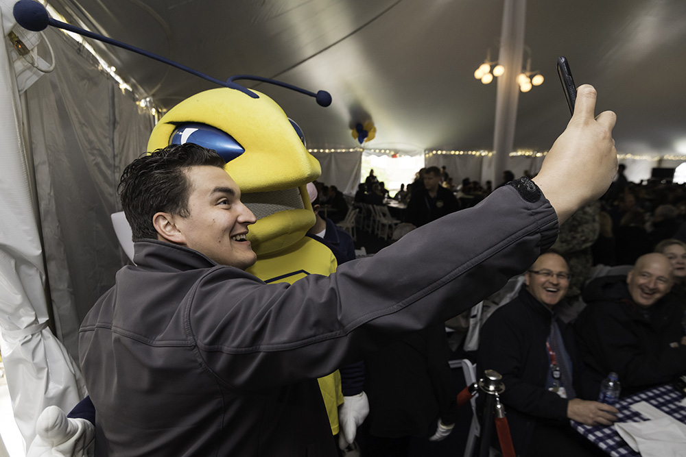 pereson takes a selfie with Rocky mascot