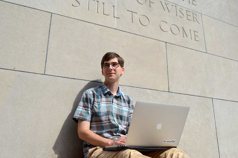 Jarrod Young using a laptop on the steps of the library.