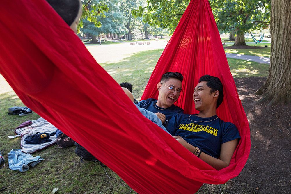 two students in a hammock, laughing.
