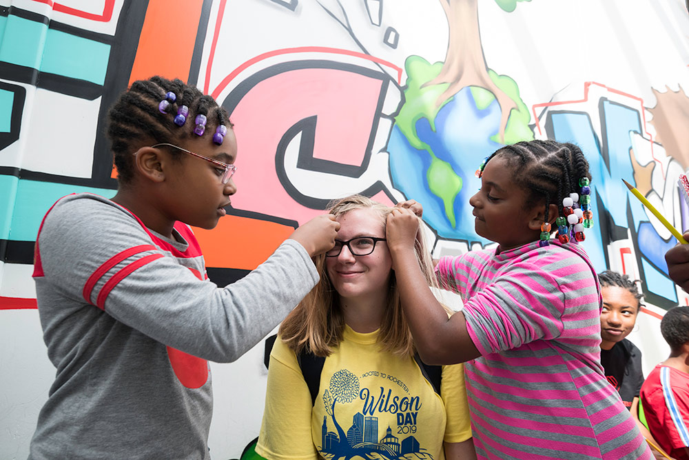 two children braiding a college student's hair.