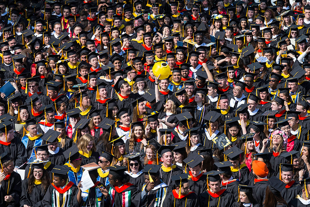 large crowd of graduates at a commencement ceremony, bouncing a beach ball. 