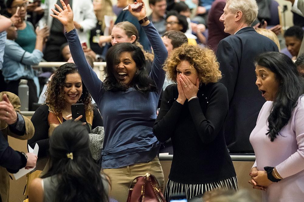 group of students jump up and down and cheer.