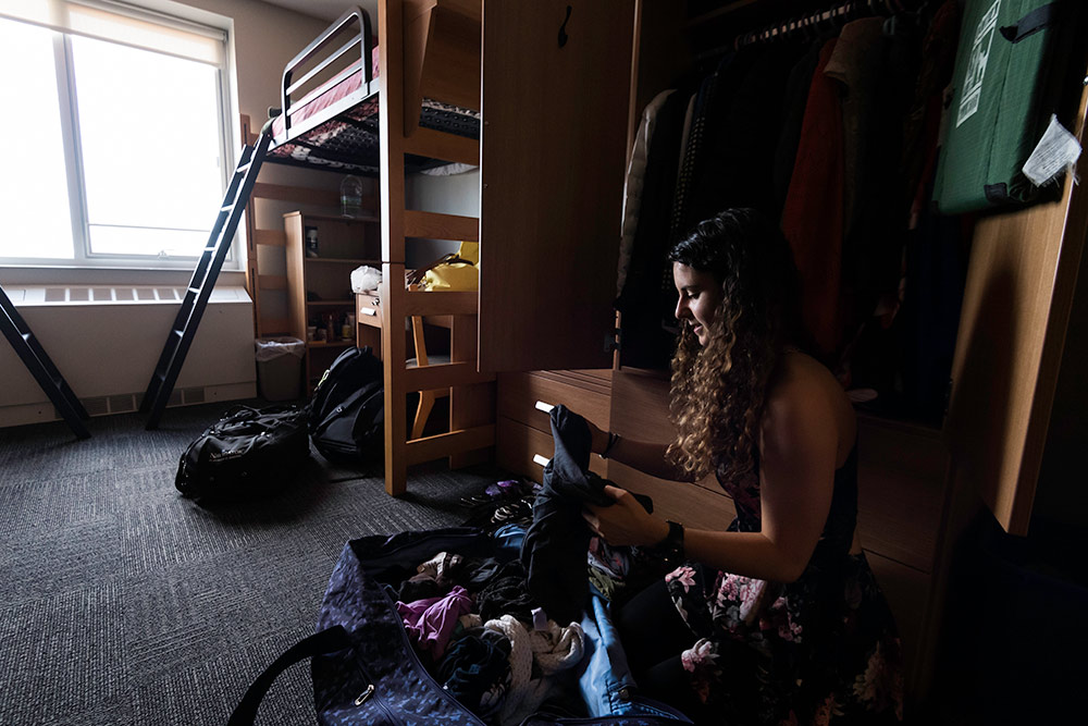 student sits on the floor in her room, unpacking.