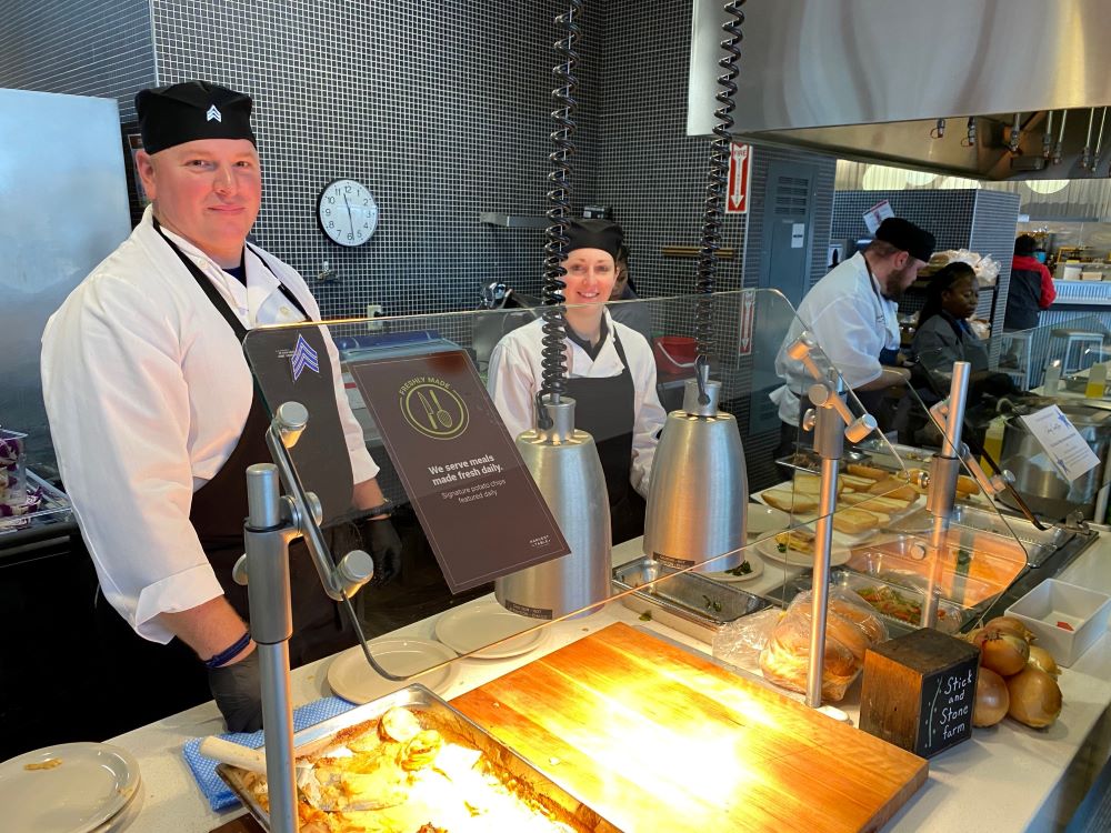 Dining Services workers behind a serving line in a dining room.