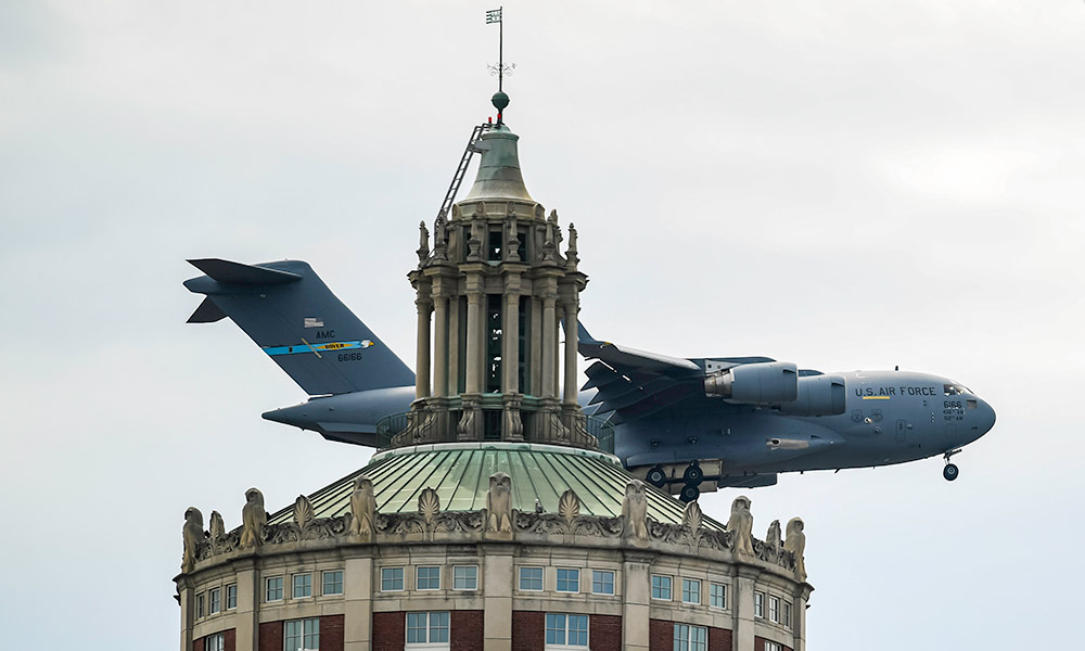 Feature image large airplane passing very closely behind Rush Rhees Library tower.