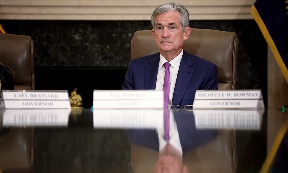 Feature image Jerome Powell sits at a conference table filled with name plates for other Fed governors.