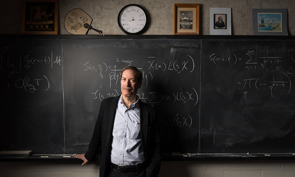Feature image Steve Gonek in front of blackboard with mathematical formula.