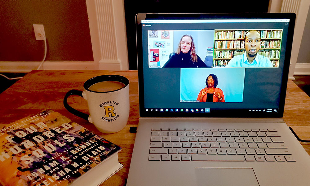 Open laptop displaying Zoom with Ibram X. Kendi and two moderators next two a University of Rochester mug of coffee and Kendi's book "Stamped from the Beginning."