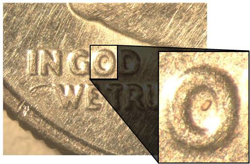 The zircon crystal sits inside the "O" on a dime, with an inset showing a zoomed-in view for scale