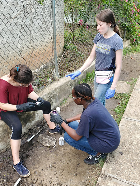 three students applying glue to a water pipe.