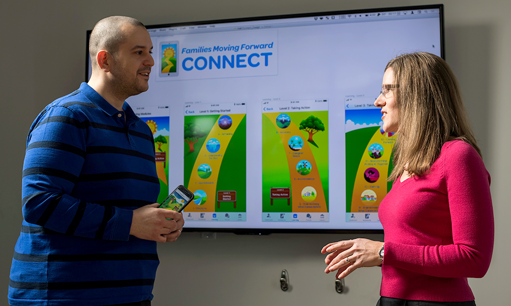 two people talking to each other in front of a large screen