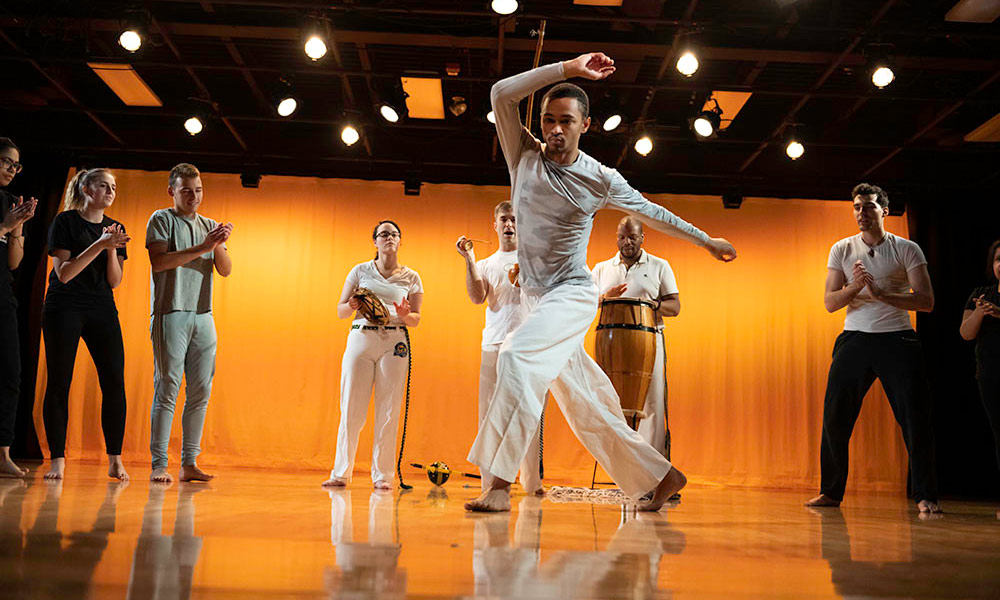 Feature image dance class with one dancer doing a demonstration in the center of a studio.