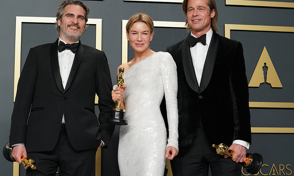 Joaquin Phoenix, Renee Zellweger, and Brad Pitt pose holding Oscar trophies.