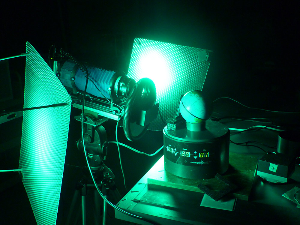 Green lights shine on panels near the globe, which sits on a small stand in front of a camera.