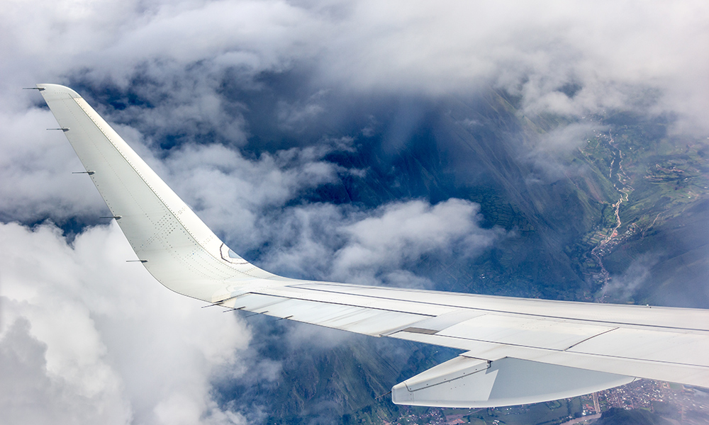 Feature image Airplane wing among the clouds over the Andes Mountains.