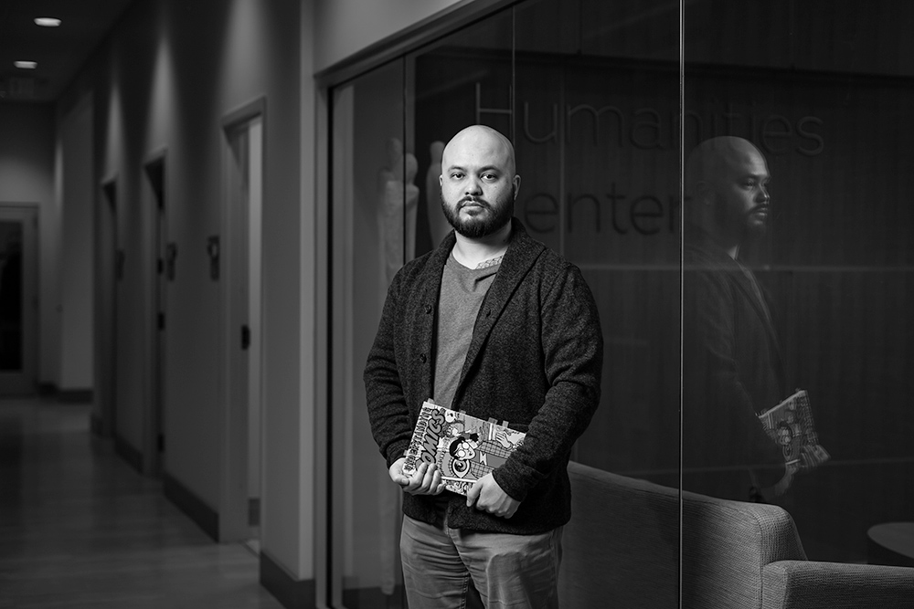 student poses for portrait holding comic books.