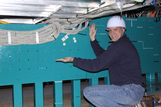 Professor Steve Manly in a hard hat points out a series of cables.