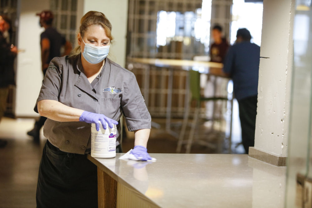 Employee Tammy Connell wears a face mask as she disinfects surfaces in the dining center.