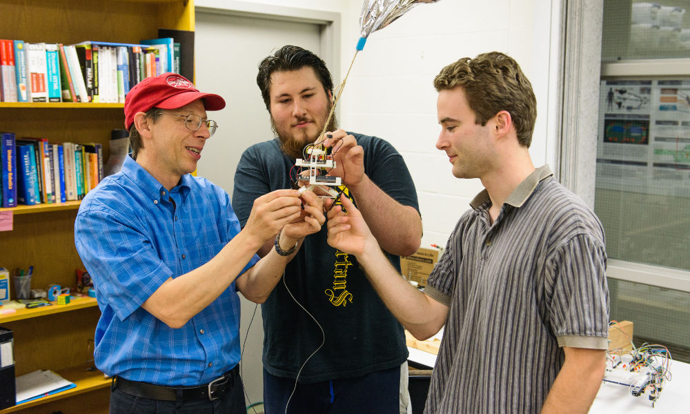 Feature image Randal Nelson and two students examine a robot blimp.