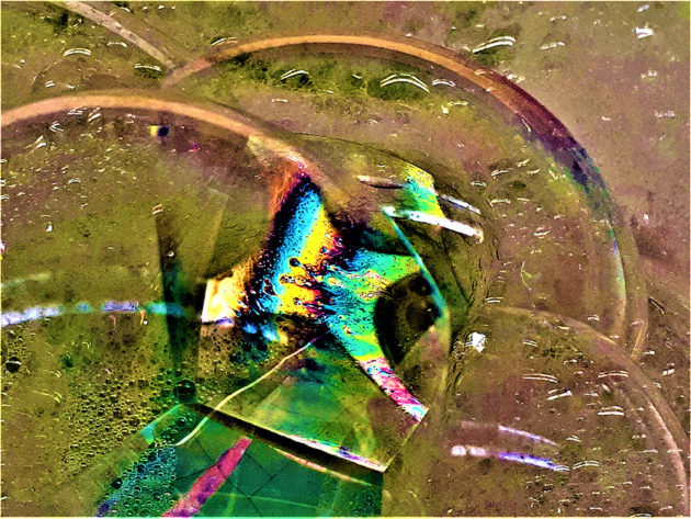 Looks like water bubbles on sand, with bright green, yellow, and turquoise reflection at center.