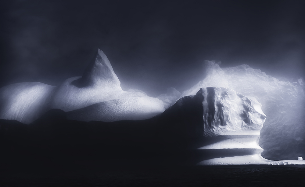 Ghostly photo of icebergs in fog at night.
