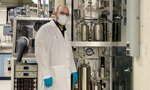 Masked, gloved researcher in chemistry lab.