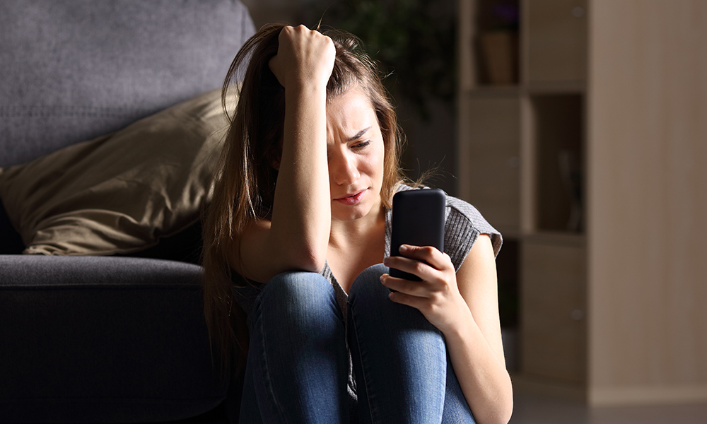 depressed teen looking at social media on phone.