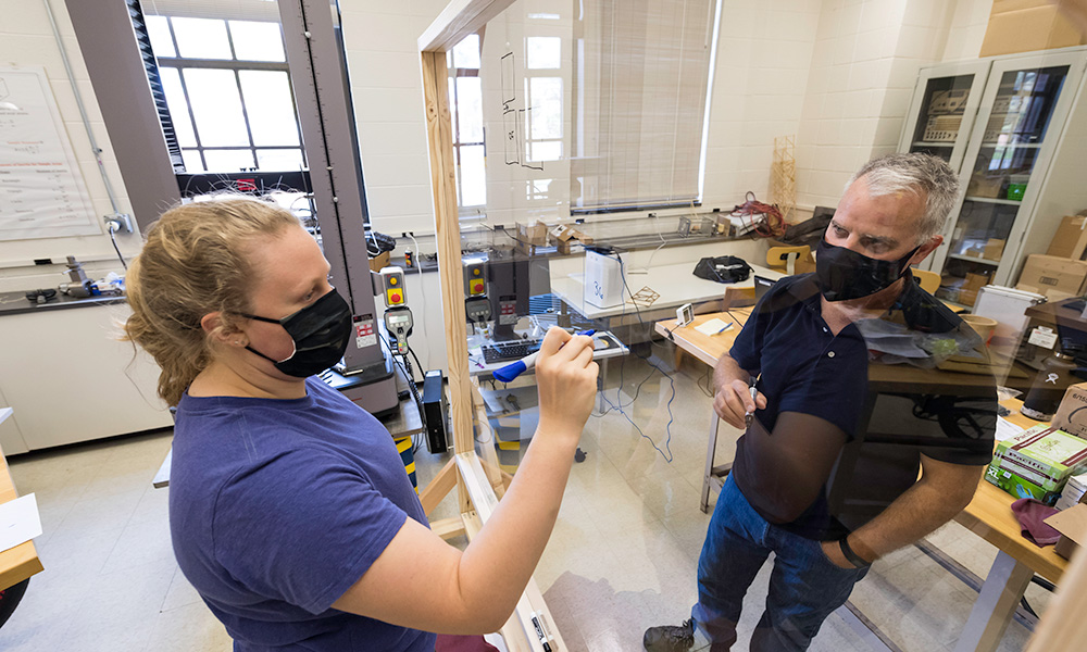 Feature image student and professor writing on opposite sides of clear pane