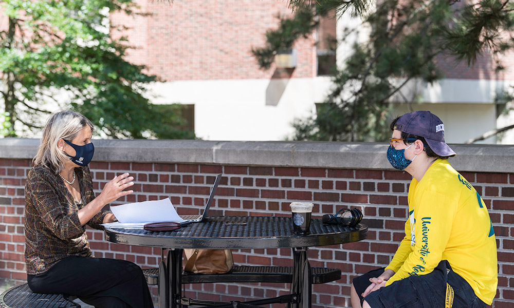 faculty member meeting outside with student