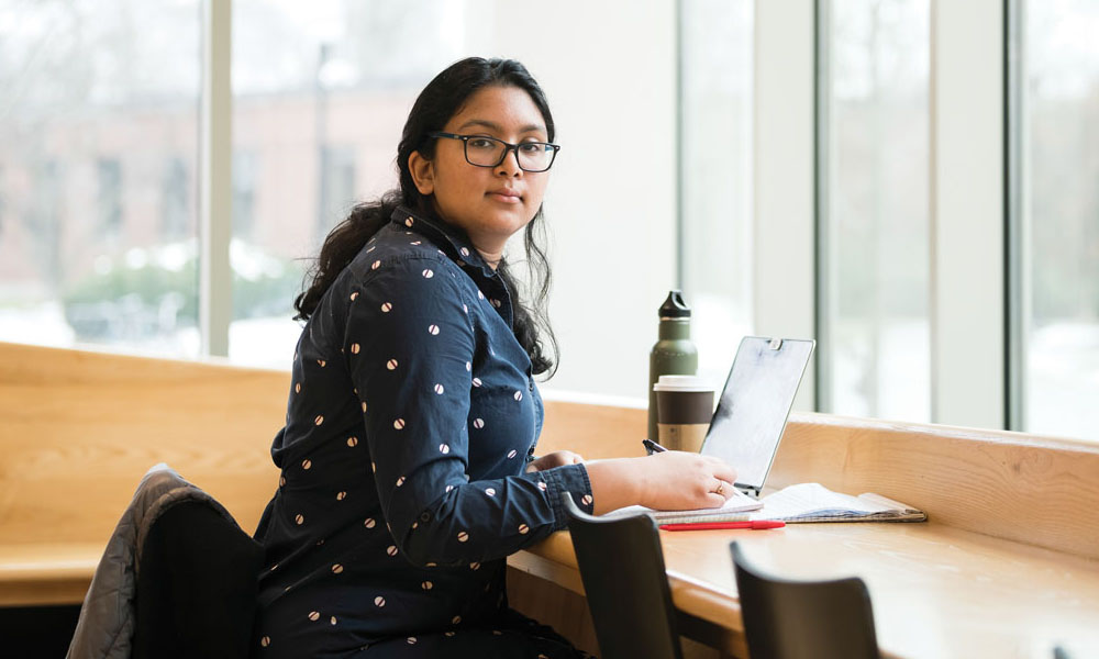 first-generation student Maisha Idris ’19 seated in study area, with laptop and water bottle.
