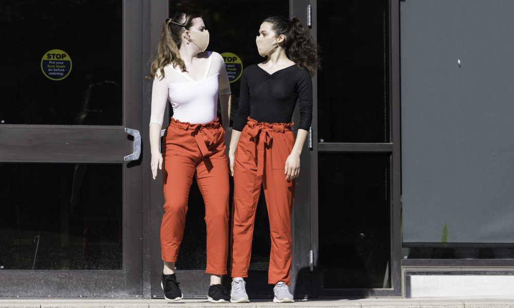 Two dancers look at each other in front of Sage Art Center.