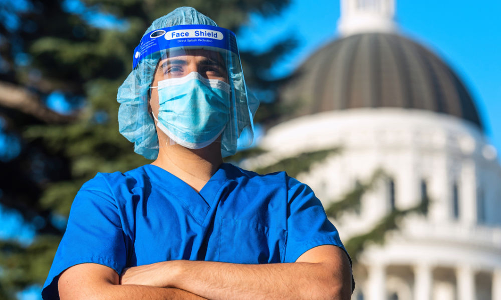 Feature image Health care worker stands in front of a capitol building.