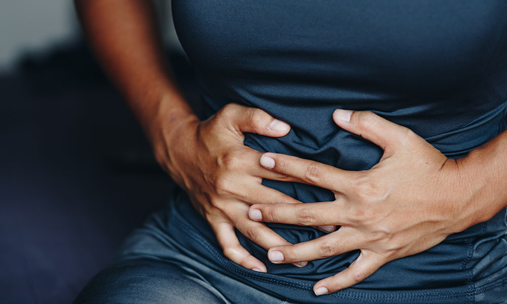 woman's hands grabbing her abdomen due to endometriosis symptoms.