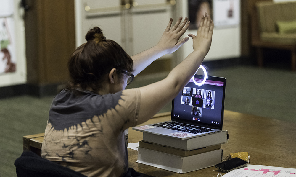 Feature image student raises hands while talking with others on the computer