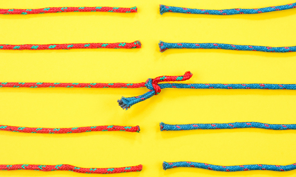 Blue and red strings tied together against yellow background.