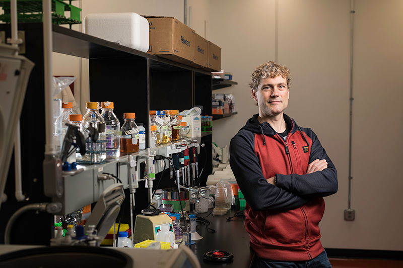 Researcher leaning against a lab bench where he studies baker's yeast.