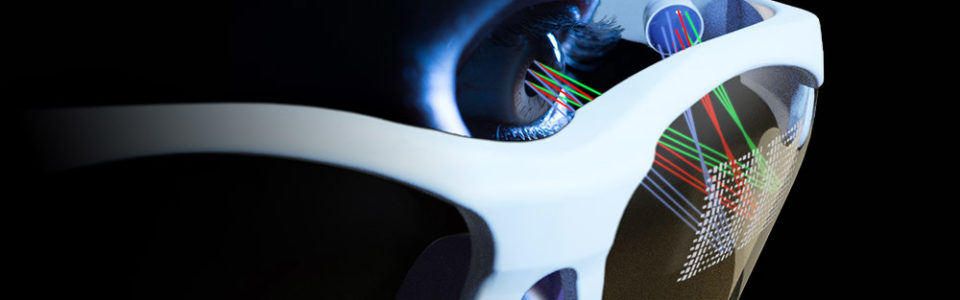 artists conception shows a close-up of a face wearing glasses with a square grid of different colored rays being projected onto the inside of one of the glasses's lenses.