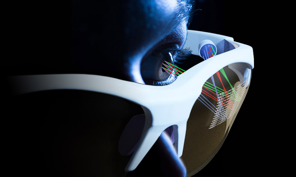 artists conception shows a close-up of a face wearing glasses with a square grid of different colored rays being projected onto the inside of one of the glasses's lenses.