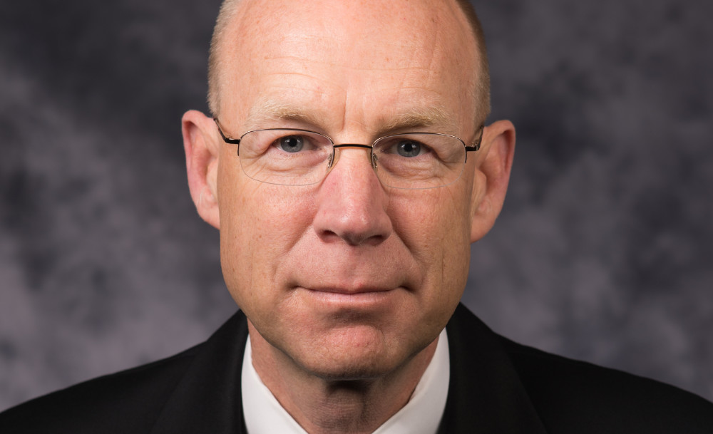 Feature image Closeup of Mark Fischer in black suit coat and white collared shirt.