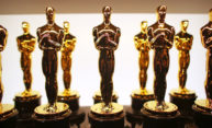 Two rows of Academy Award statuettes lined up backstage.