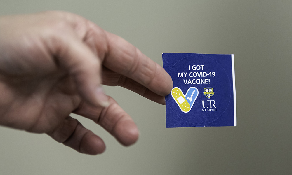 Feature image hand holding vaccination sticker